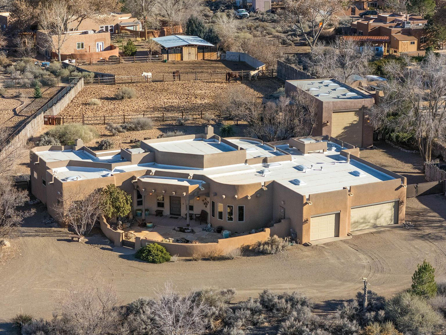 Elevated aerial showing the single-level home, workshop, and horse corrals