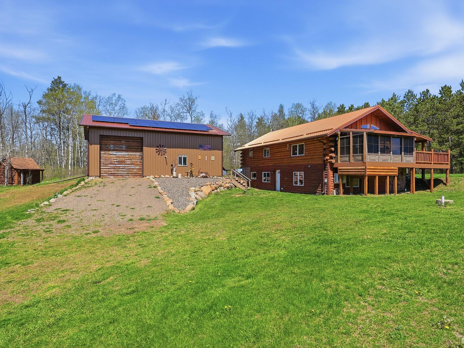 Wide shot of log home, garage with solar panels, and green lawn