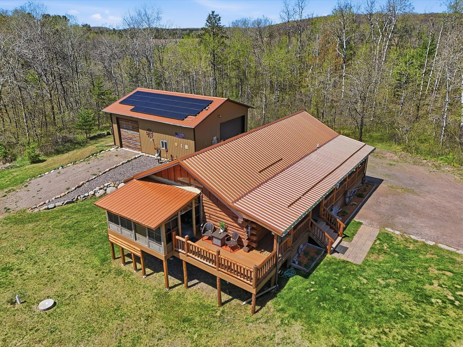 Aerial view of log home and detached garage with solar panels on 1 acre