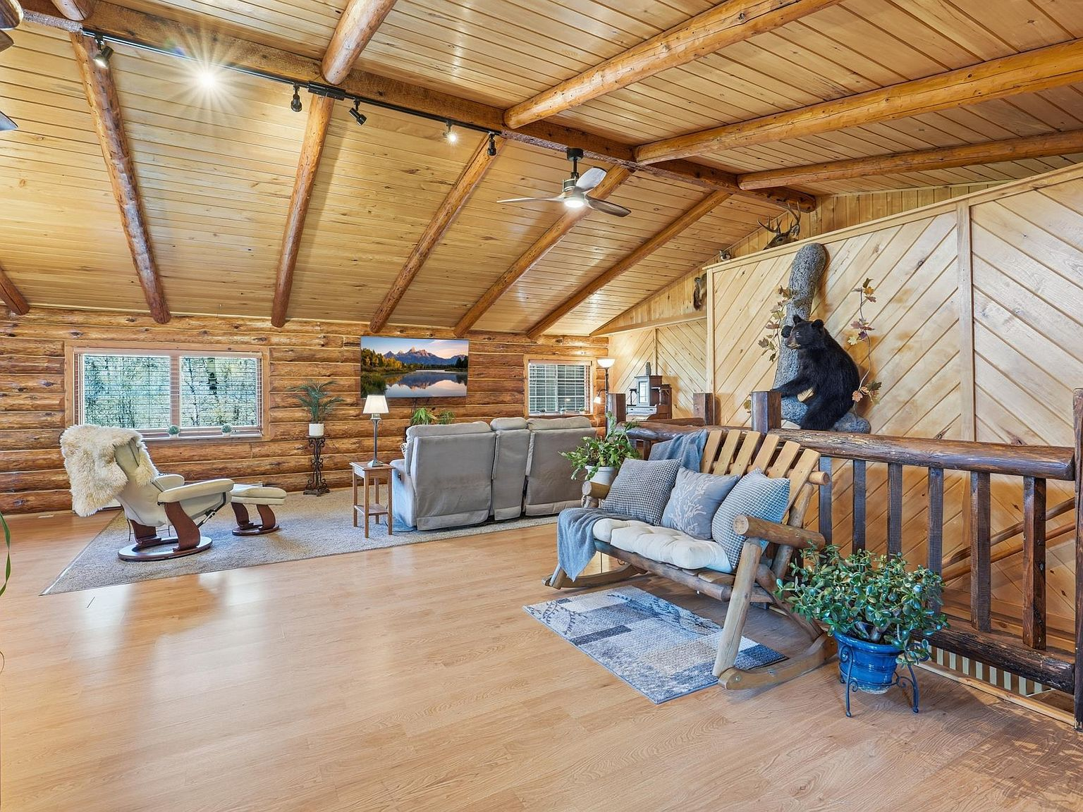 Loft living room with log walls, vaulted ceiling, and timber beams