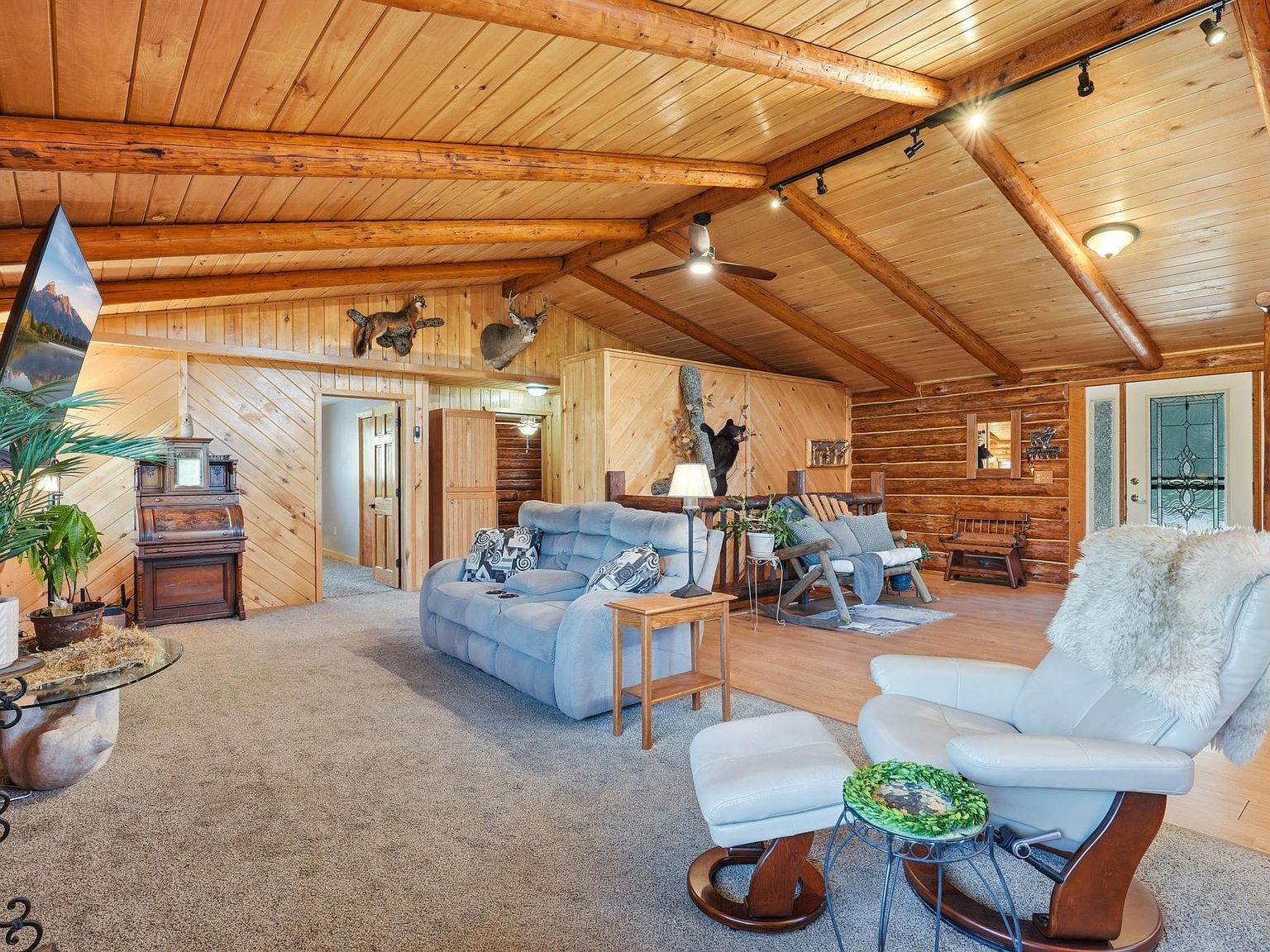 Living room with log walls, vaulted ceiling, and exposed beams