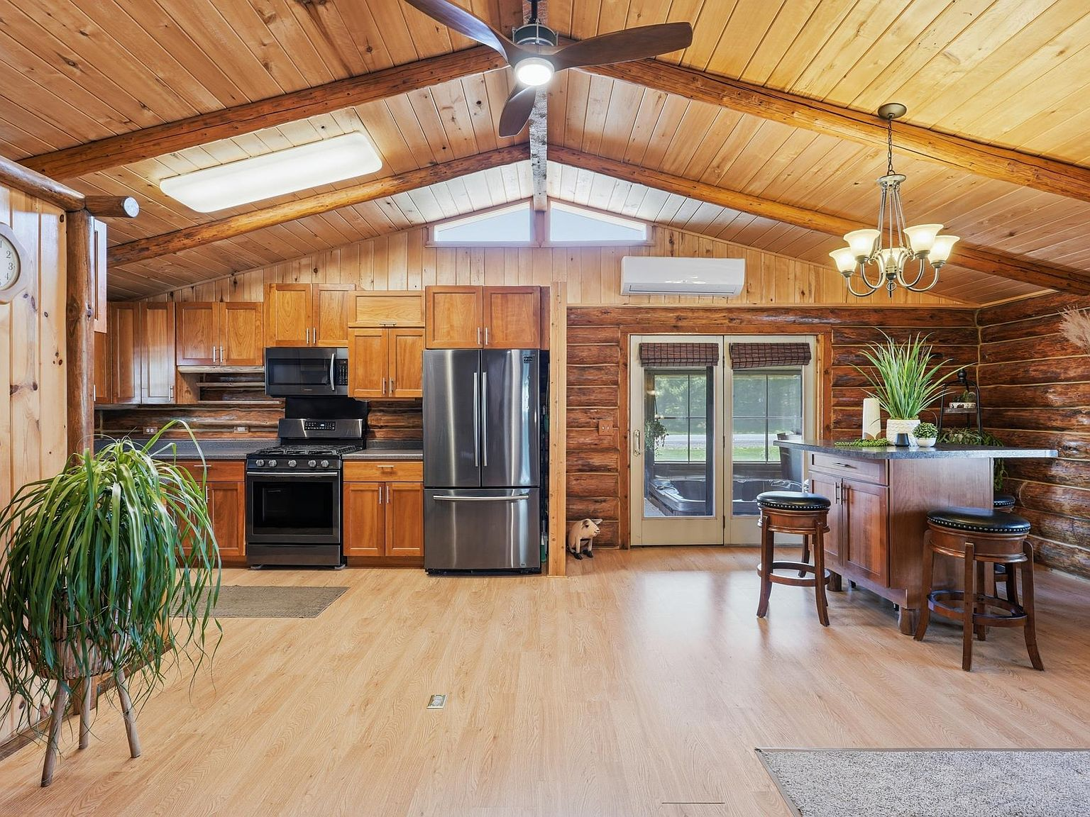 Open-concept kitchen and living area with log walls