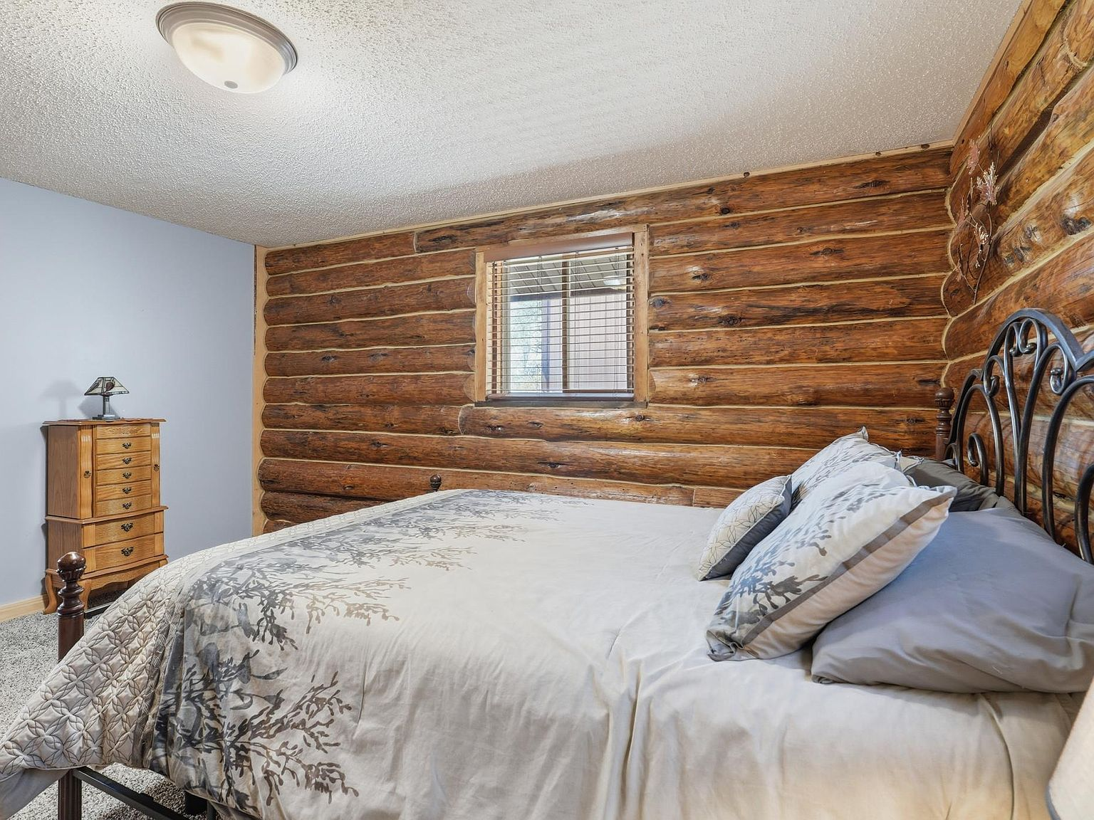 Bedroom with exposed log walls and blue-gray accent wall