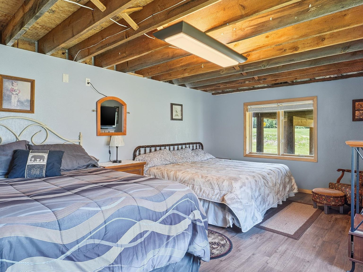 Bedroom with two beds, exposed wood ceiling joists, and light blue walls