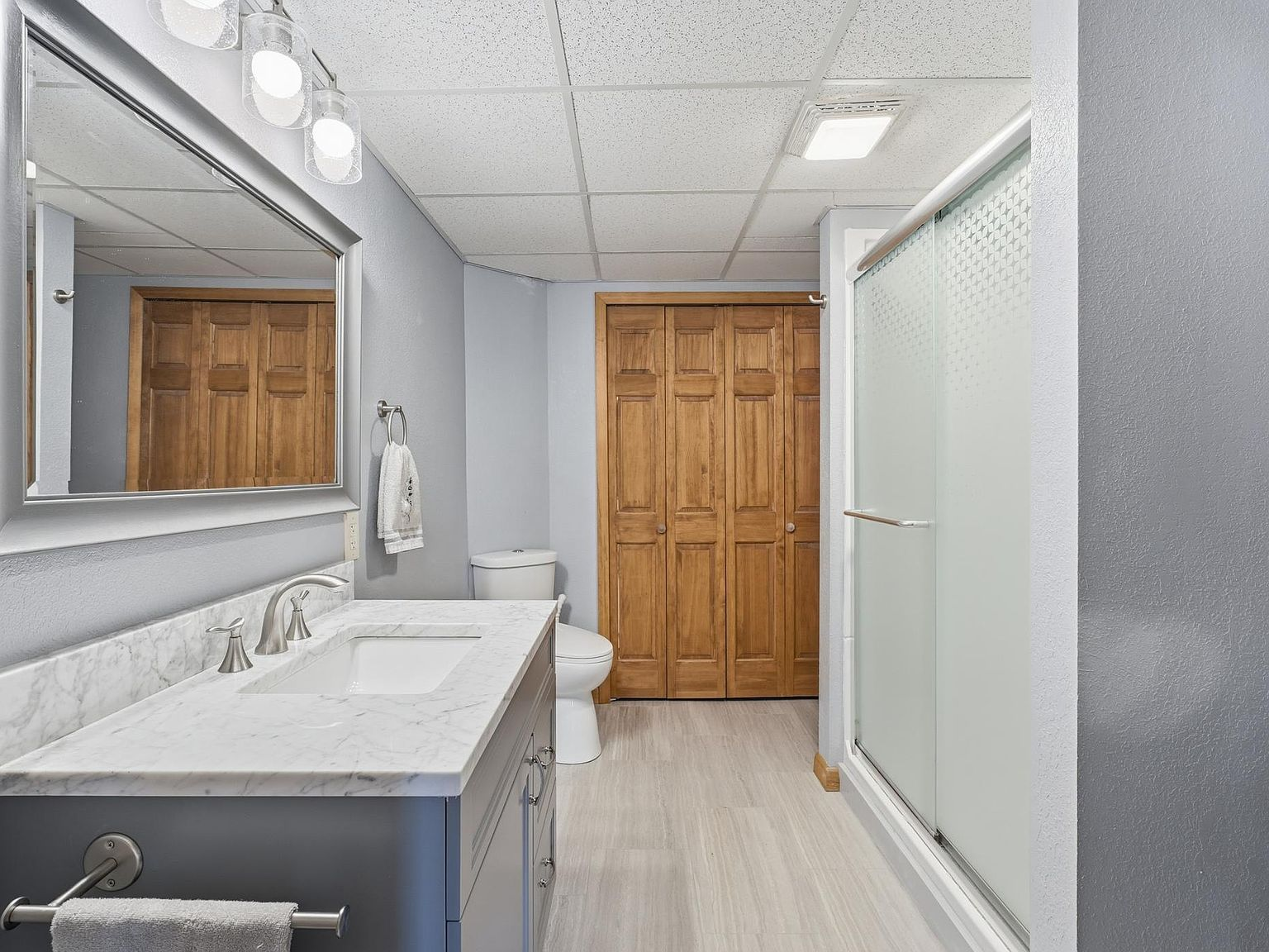 Bathroom with updated vanity, marble countertop, and shower