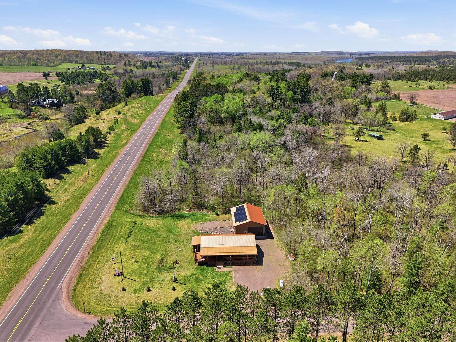 Aerial view showing solar panels on garage roof and paved road