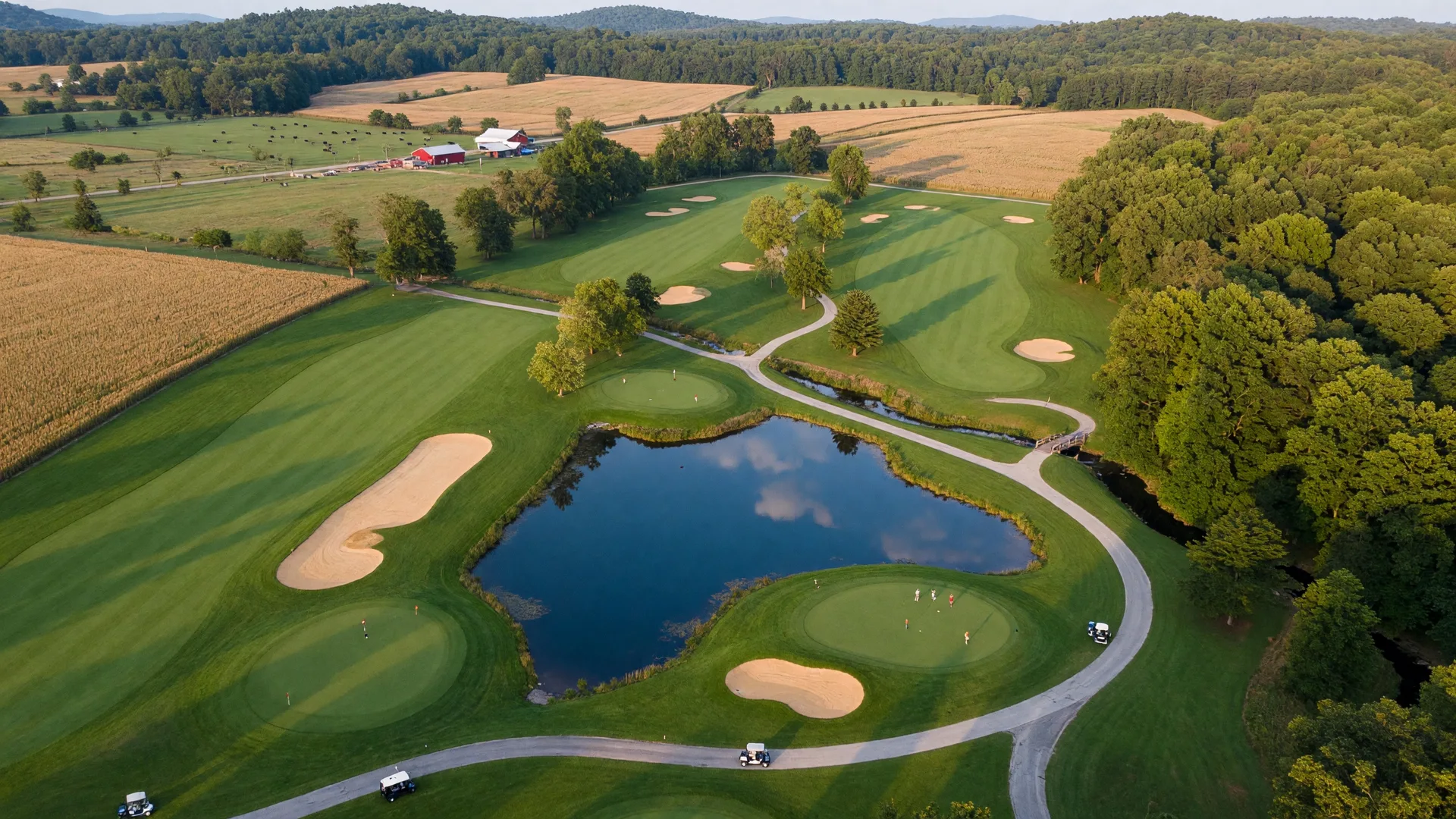 Aerial view of a championship golf course in Virginia countryside with rolling fairways, sand traps, and a pond surrounded by trees