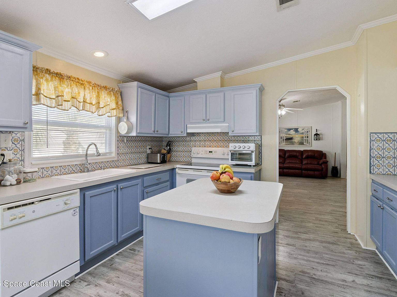 Kitchen with light blue cabinets, white countertops, and skylight