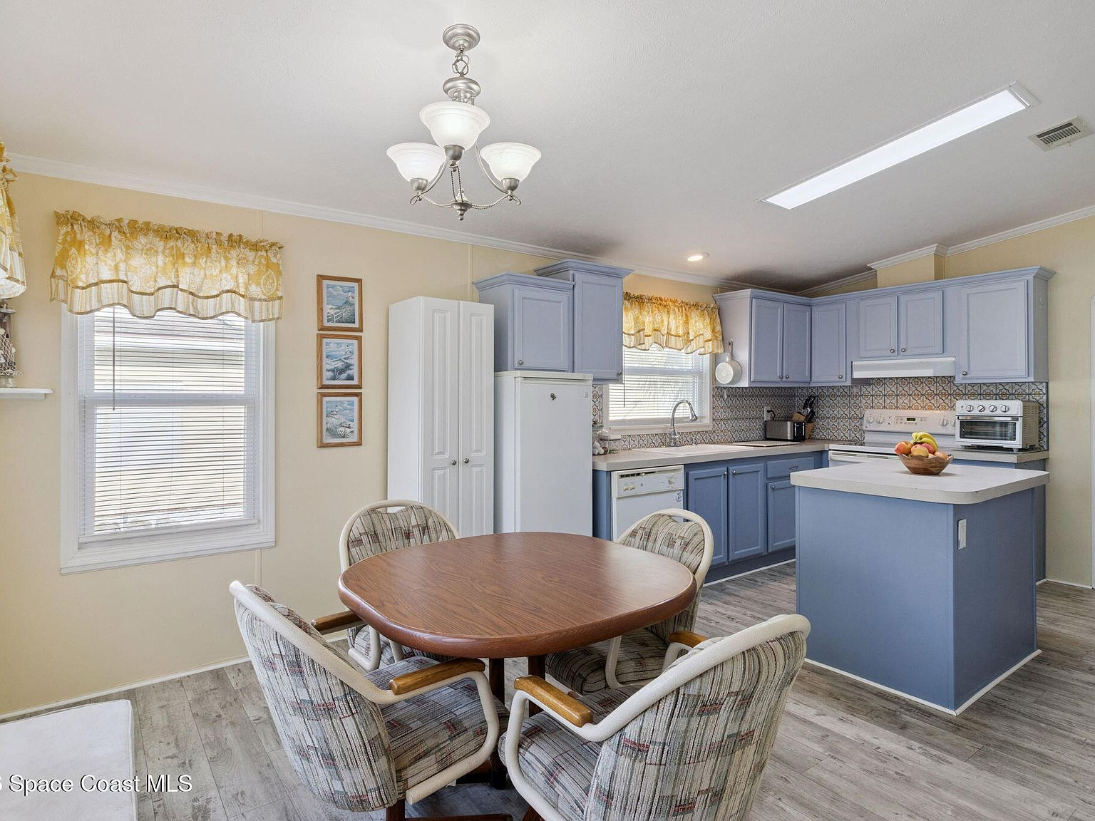 Kitchen-dining combo with blue cabinetry and grey laminate flooring