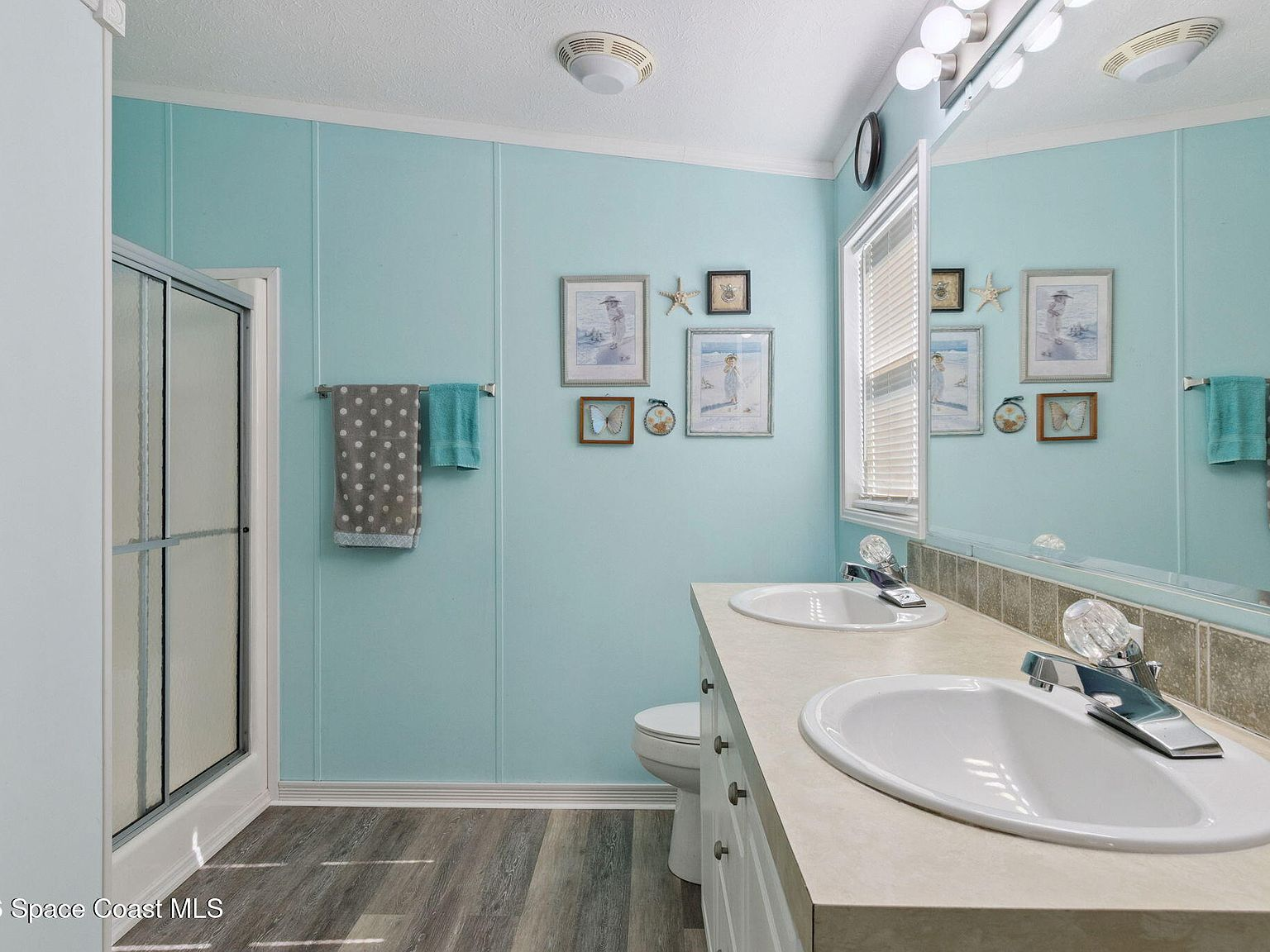 Bathroom with light blue paneled walls and white double sink vanity