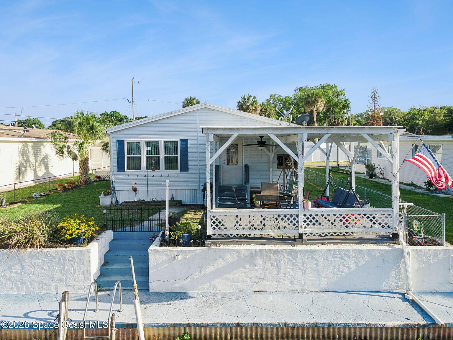Waterfront exterior view of 3100 Mark Ln showing light blue siding and white covered porch