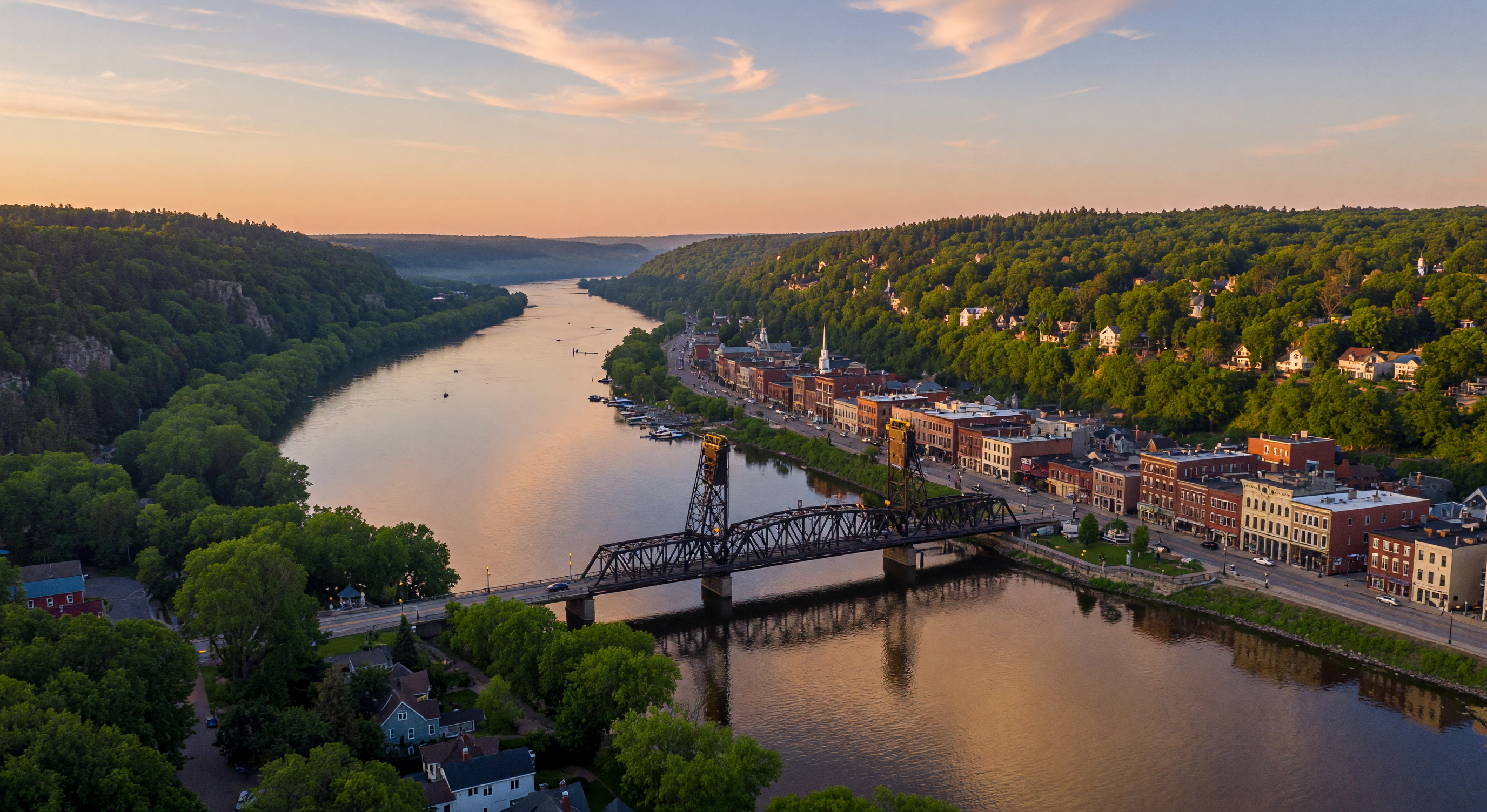 Aerial view of Stillwater, Minnesota and the St. Croix River valley at golden hour, with the historic lift bridge and downtown nestled between forested bluffs
