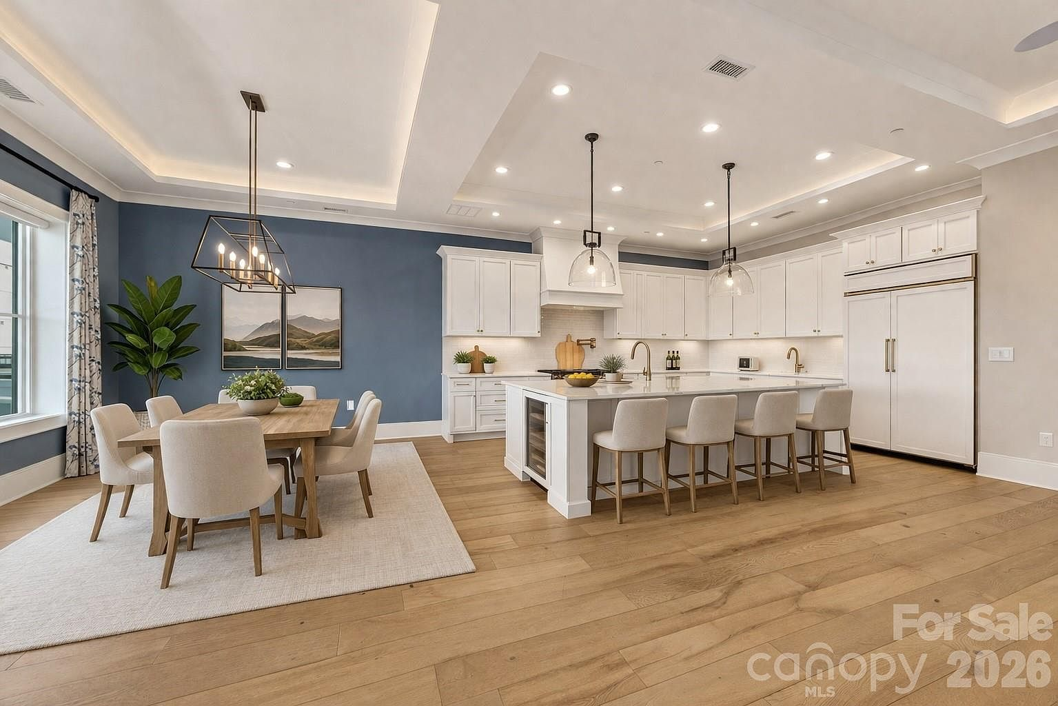 Open-concept kitchen and dining area with white cabinetry and blue accent wall