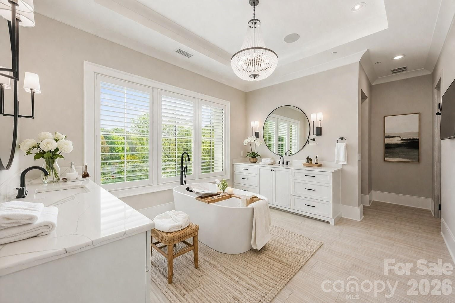 Primary bathroom with dual vanities, marble-look counters, and crystal chandelier
