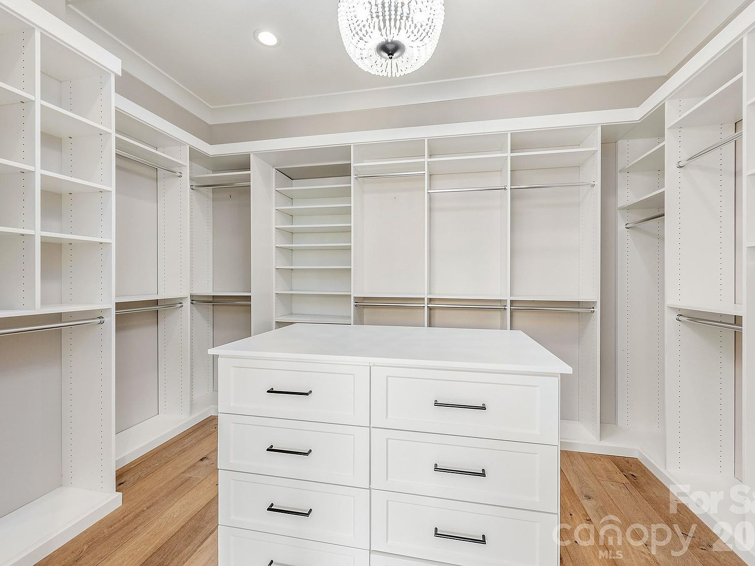 Master walk-in closet with custom built-in shelving, central island, and crystal chandelier