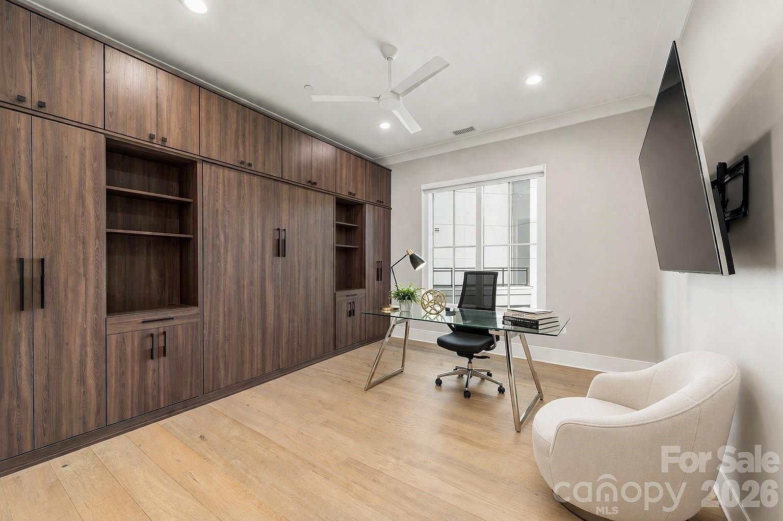 Home office with dark wood built-in cabinets, desk, and natural light