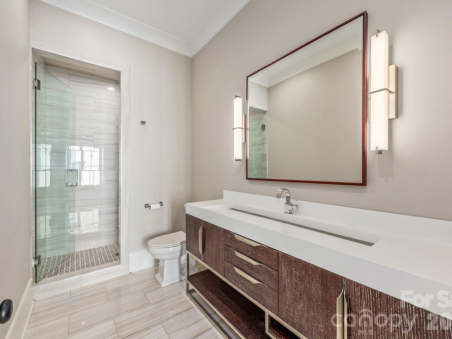 Bathroom with dark wood vanity, integrated trough sink, and glass walk-in shower