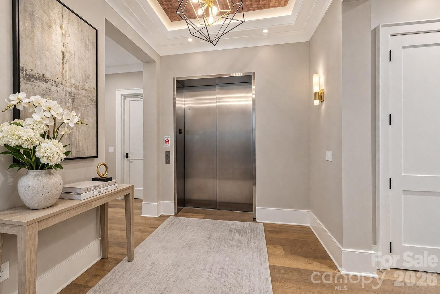 Private elevator lobby with light oak floors, copper tray ceiling, and stainless steel elevator doors