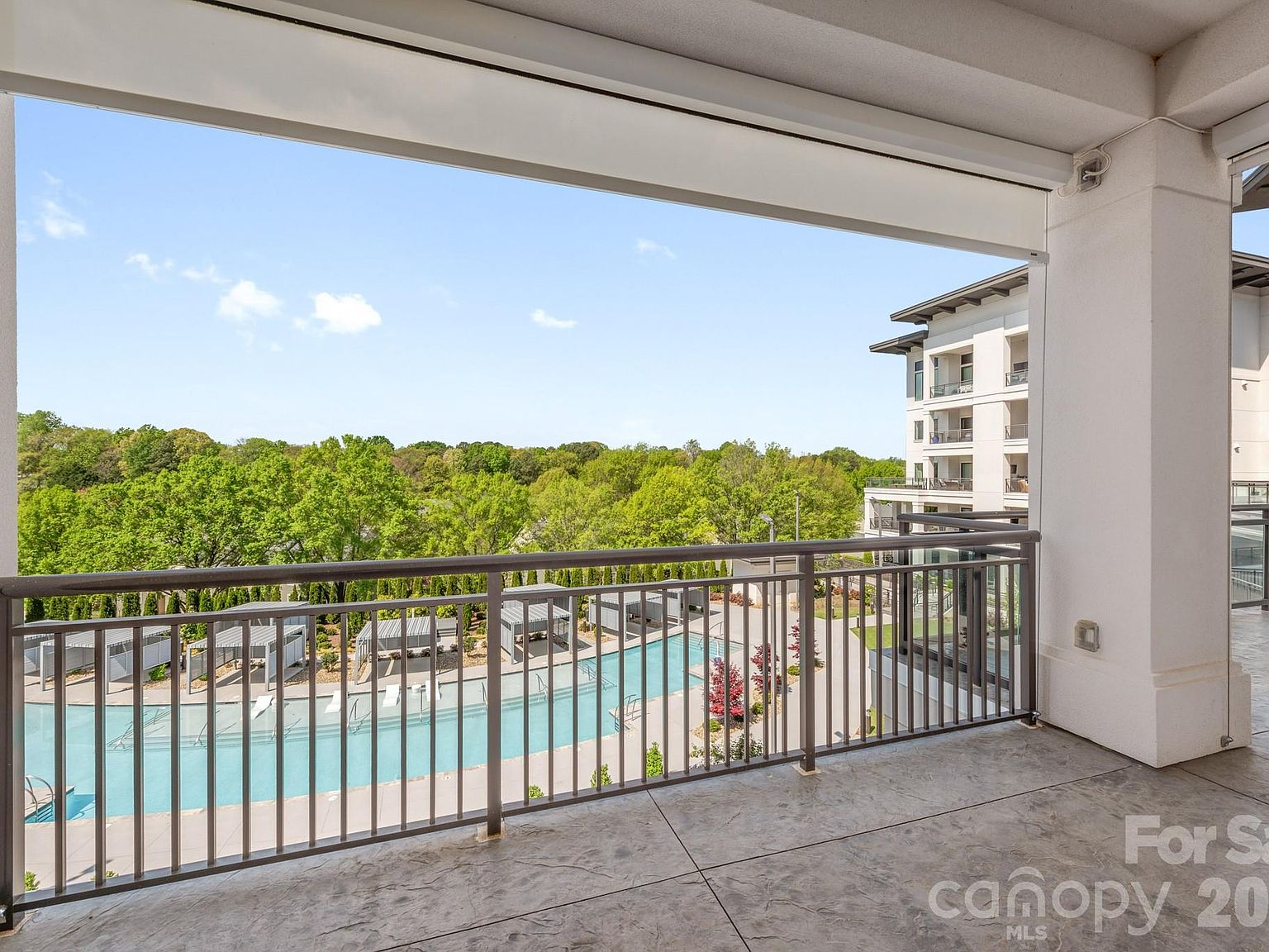 View from covered balcony overlooking the community pool and cabanas