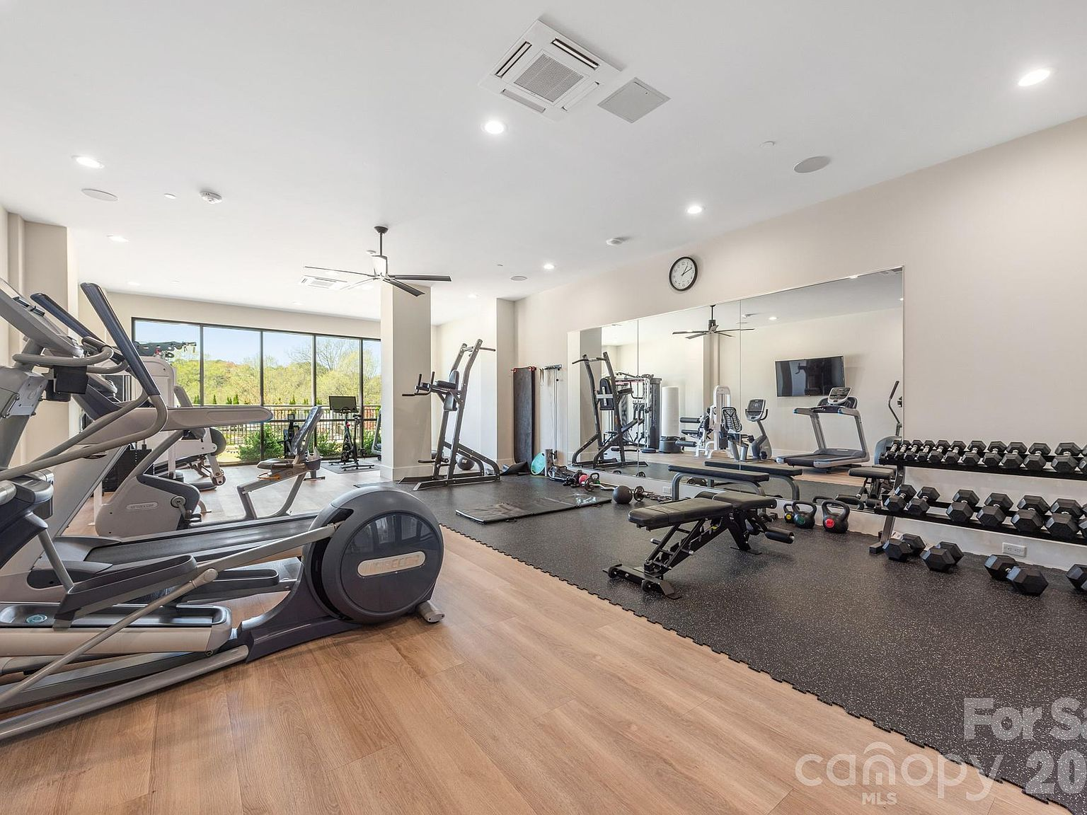 Fitness center with cardio equipment, mirrored wall, and natural light
