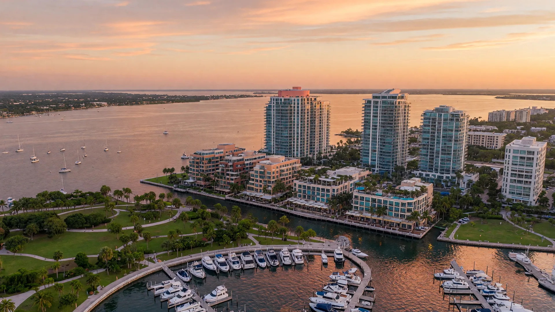 Aerial view of Downtown Sarasota Florida — luxury high-rises along Sarasota Bay at golden hour with marina and Bayfront Park