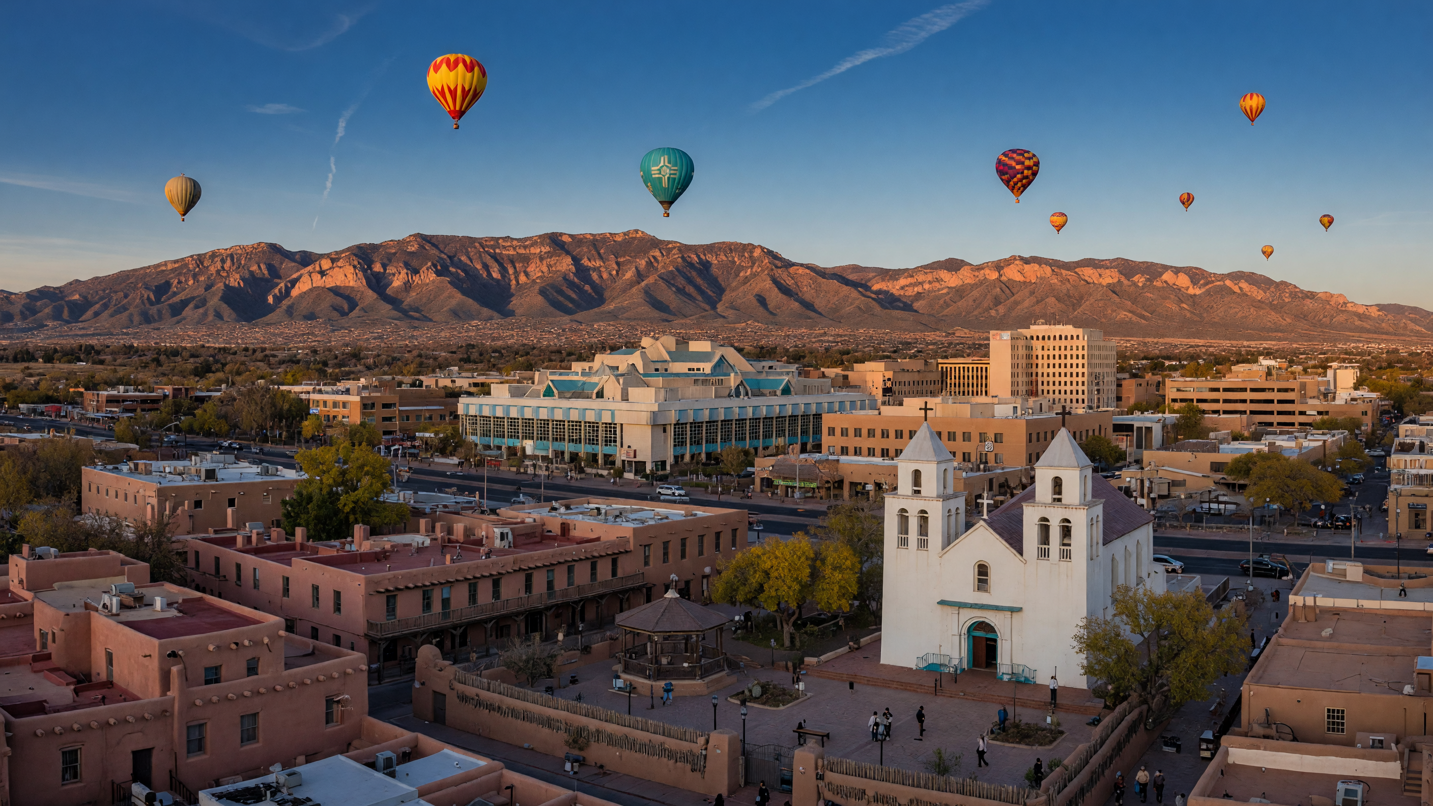 Panoramic view of Downtown Albuquerque and Old Town with historic adobe buildings, San Felipe de Neri Church, and the Sandia Mountains in the background