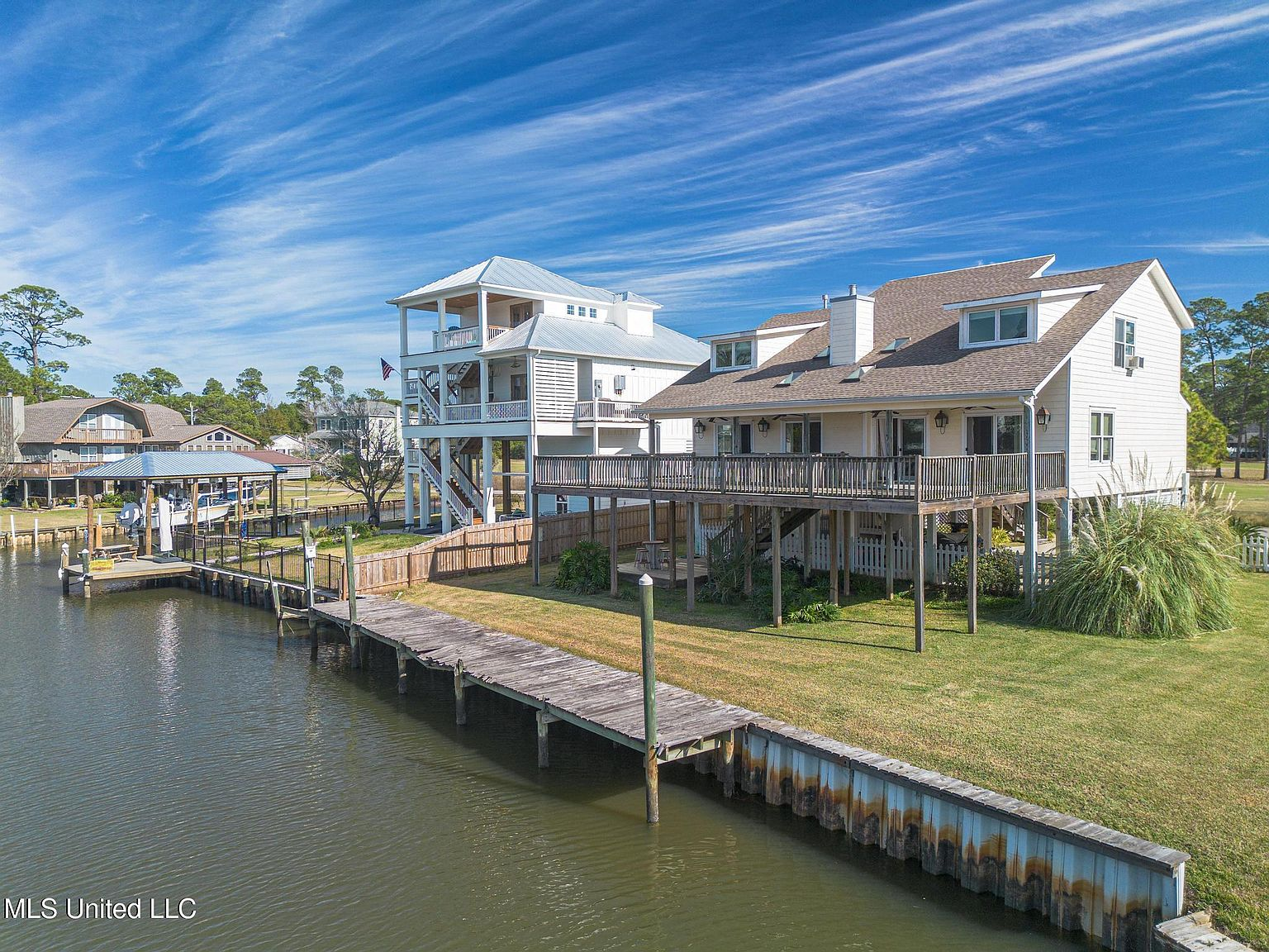 Aerial view of 231 Fairway Dr showing the elevated stilt home, private dock, and canal access in Timber Ridge