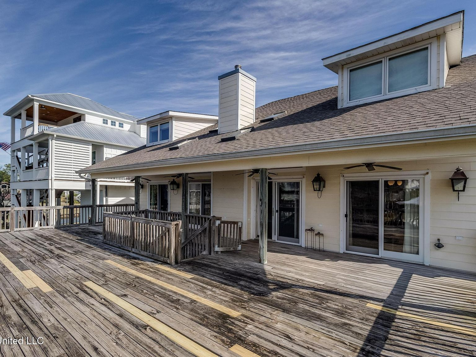 Rear exterior deck with weathered wood, shingle roof, and copper lanterns