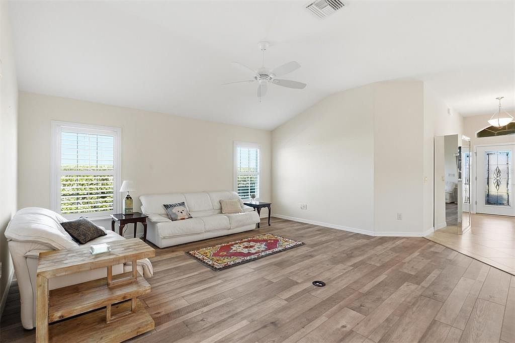 Living room view toward entry with wood-look laminate flooring and vaulted ceilings