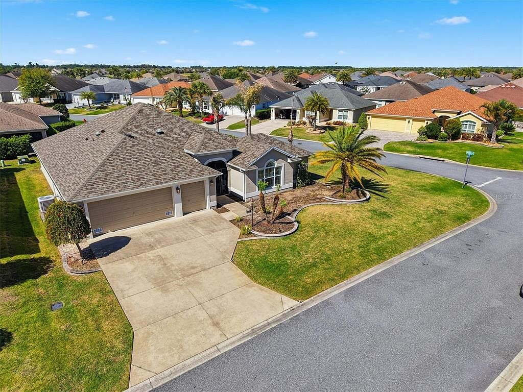 High-angle aerial of the corner lot home with palm trees and blue sky