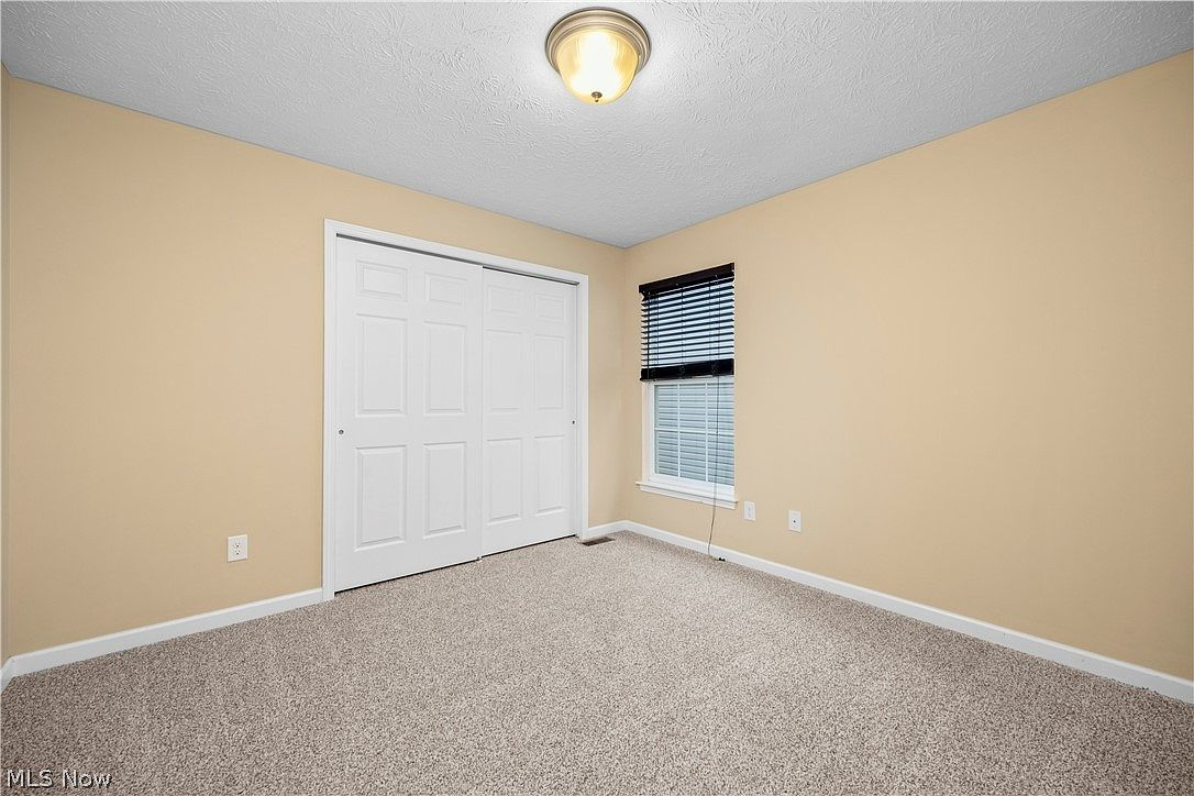 Vacant bedroom with beige carpeting and closet