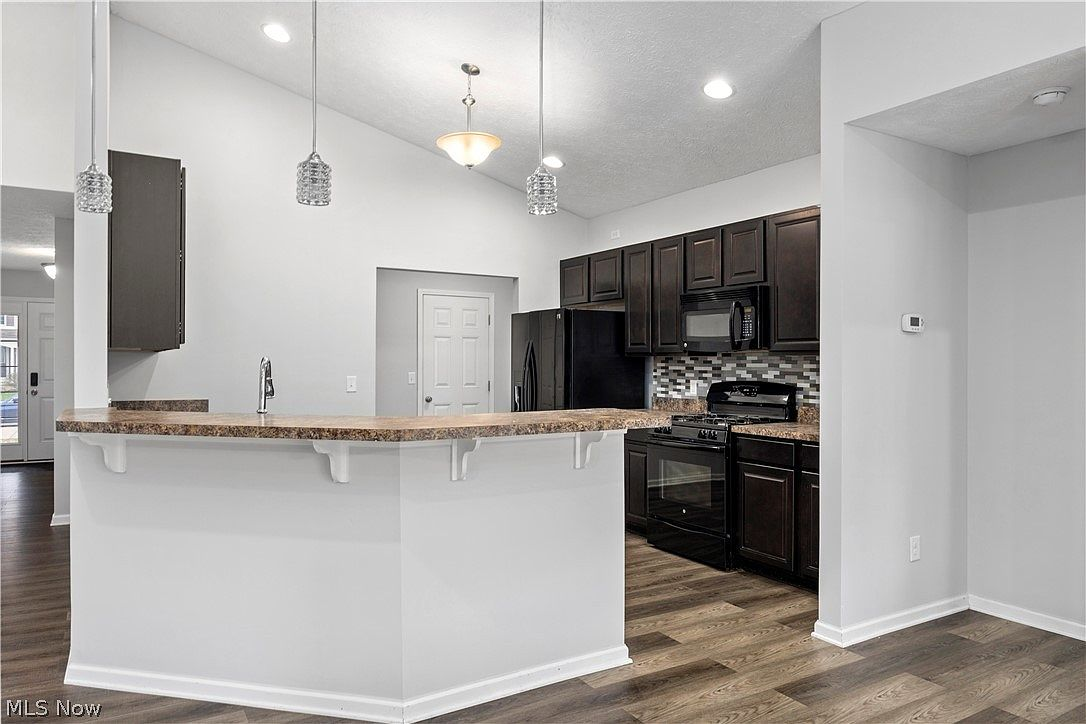 Kitchen with dark wood cabinets, breakfast bar, and pendant lighting