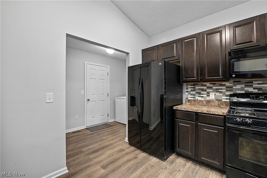 Kitchen with dark cabinets, gas range, and tile backsplash