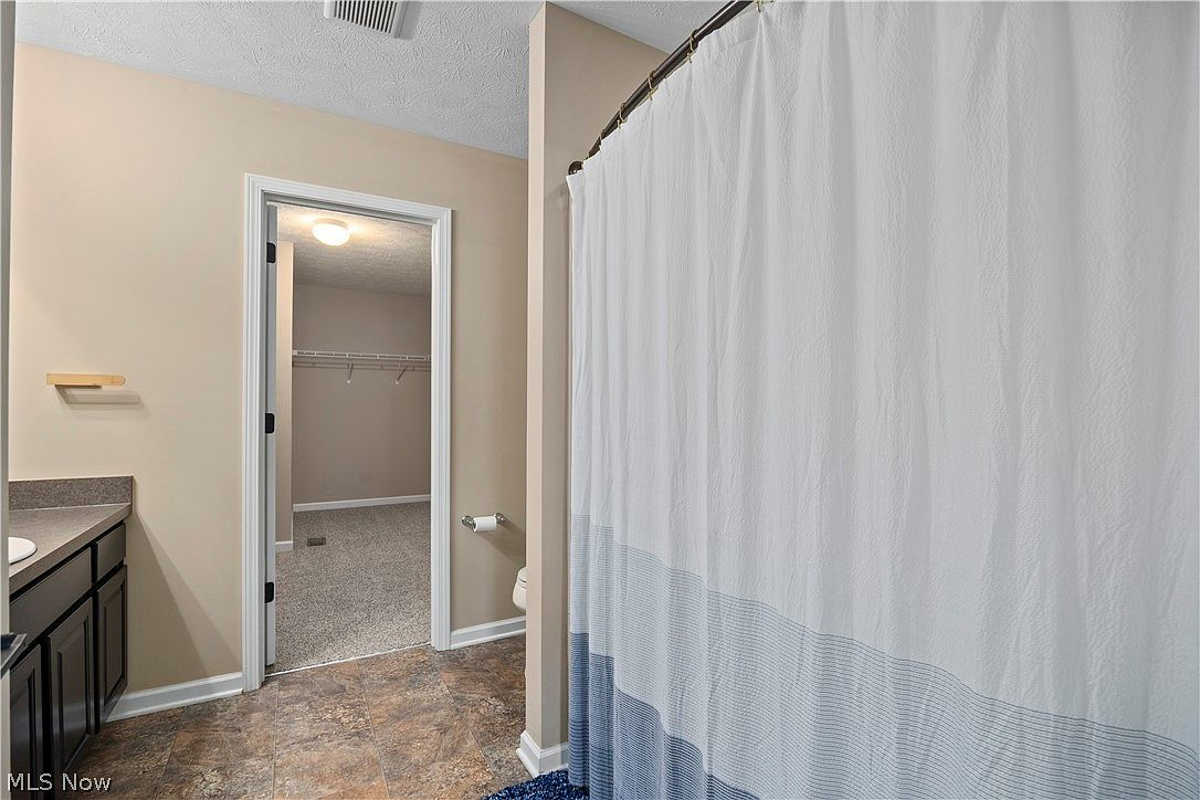 Bathroom looking through to an attached walk-in closet
