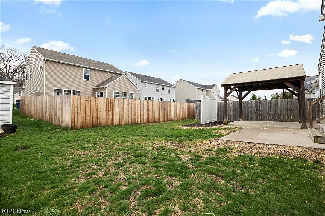 Backyard with wooden gazebo, concrete patio, and privacy fence