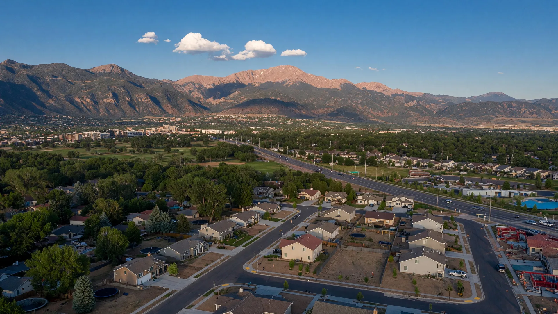 Aerial view of Colorado Springs neighborhoods with Pikes Peak towering in the background on a clear summer afternoon