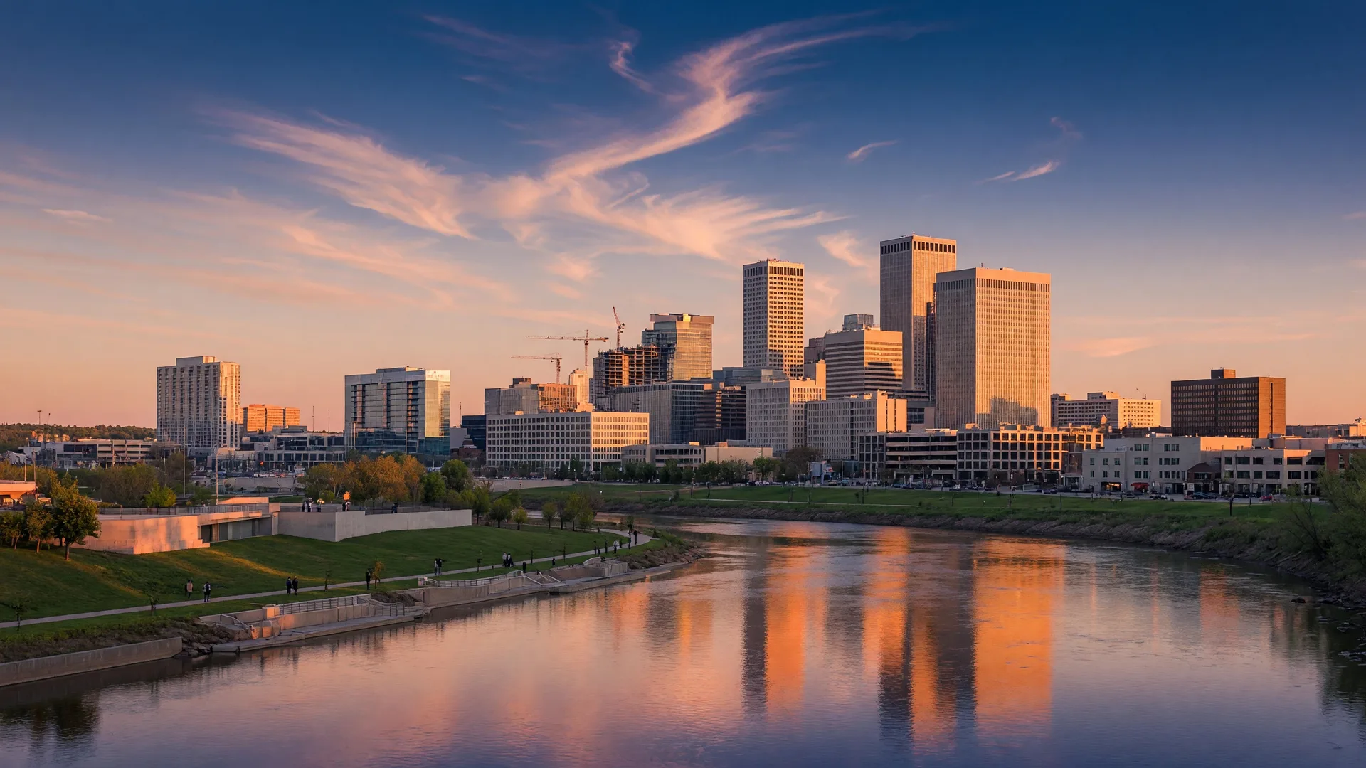 Tulsa Oklahoma skyline at golden hour with the Arkansas River and corporate buildings reflecting warm sunset light