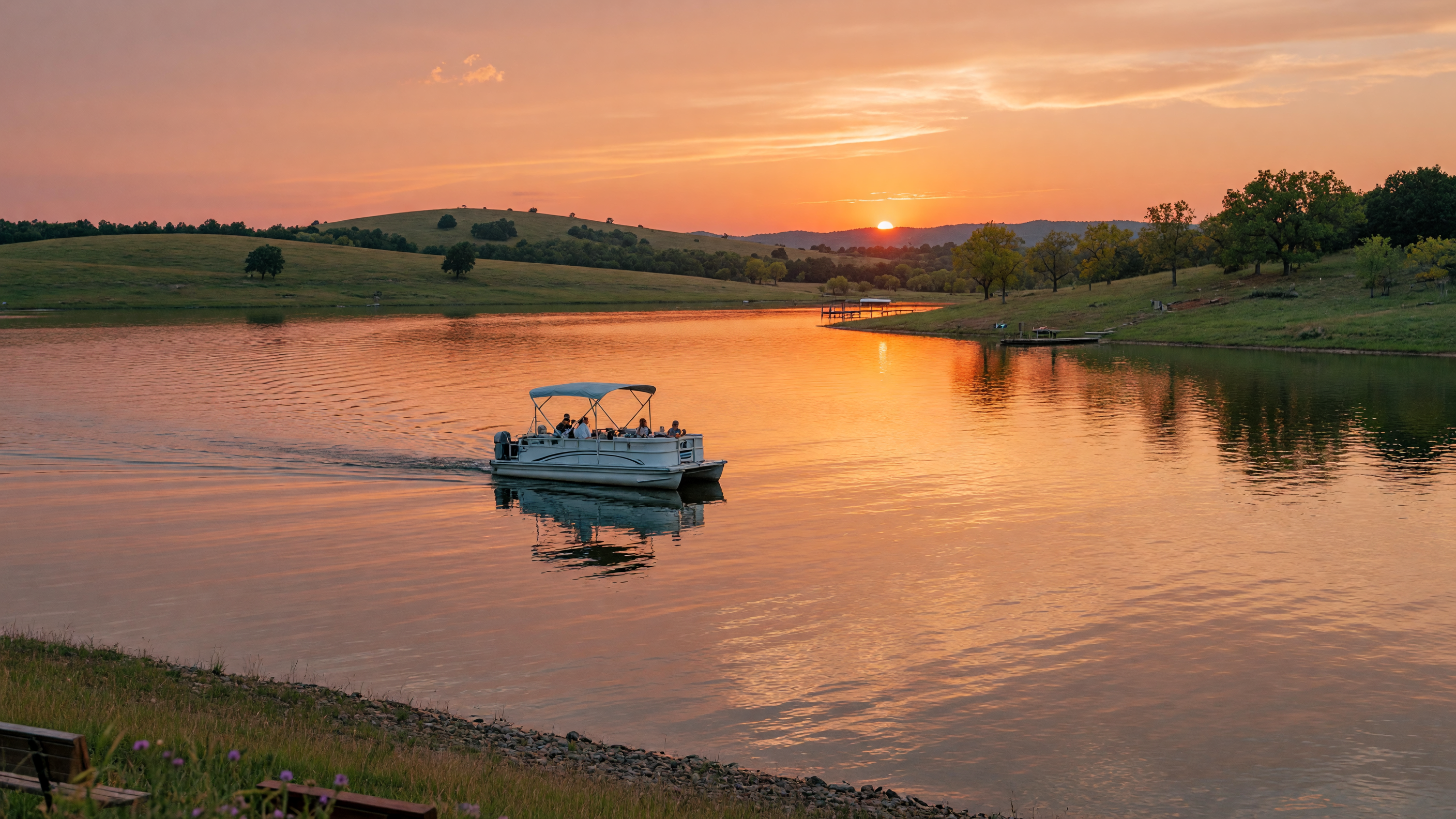 A scenic view of an Oklahoma lake at golden hour with a boat on calm shimmering water