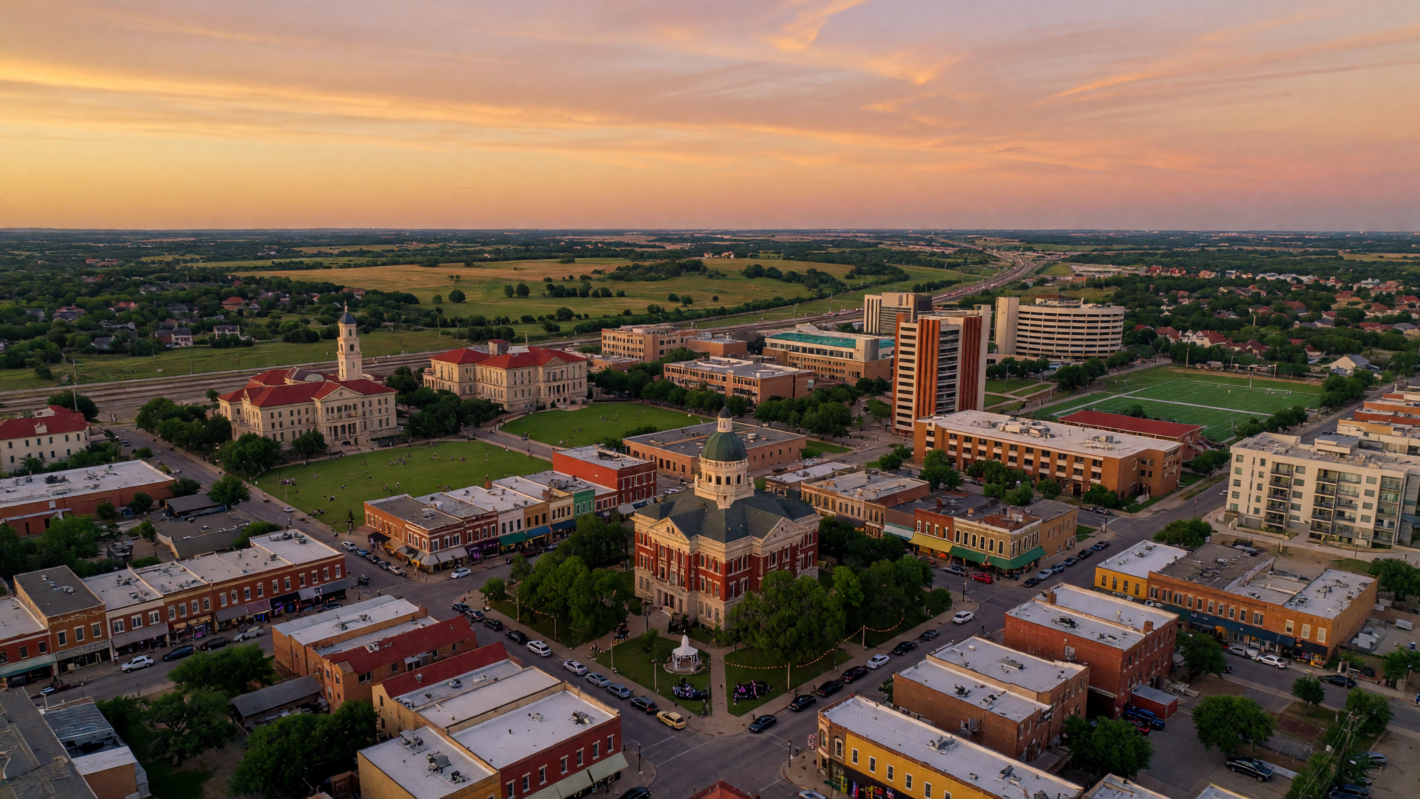 Aerial view of downtown Denton, Texas at golden hour, historic courthouse square, UNT campus, and the vibrant cityscape of North Texas's most distinctive college town