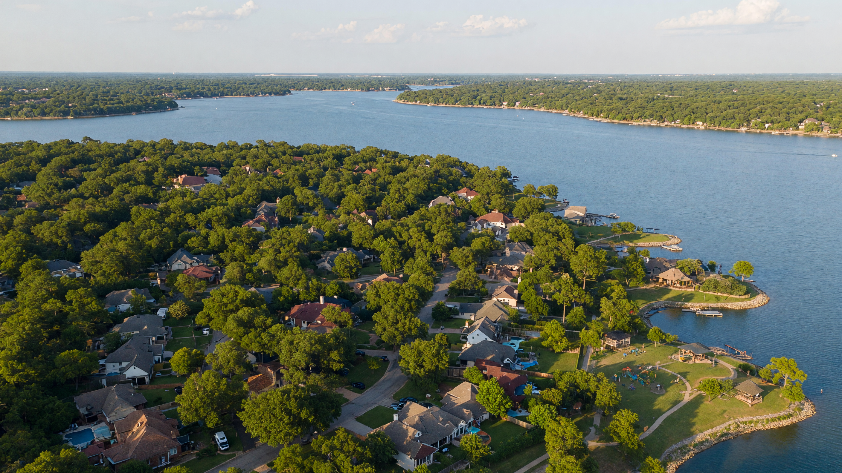Aerial view of Flower Mound, Texas showing Lake Lewisville shoreline, mature tree canopy, and established residential neighborhoods on a sunny afternoon