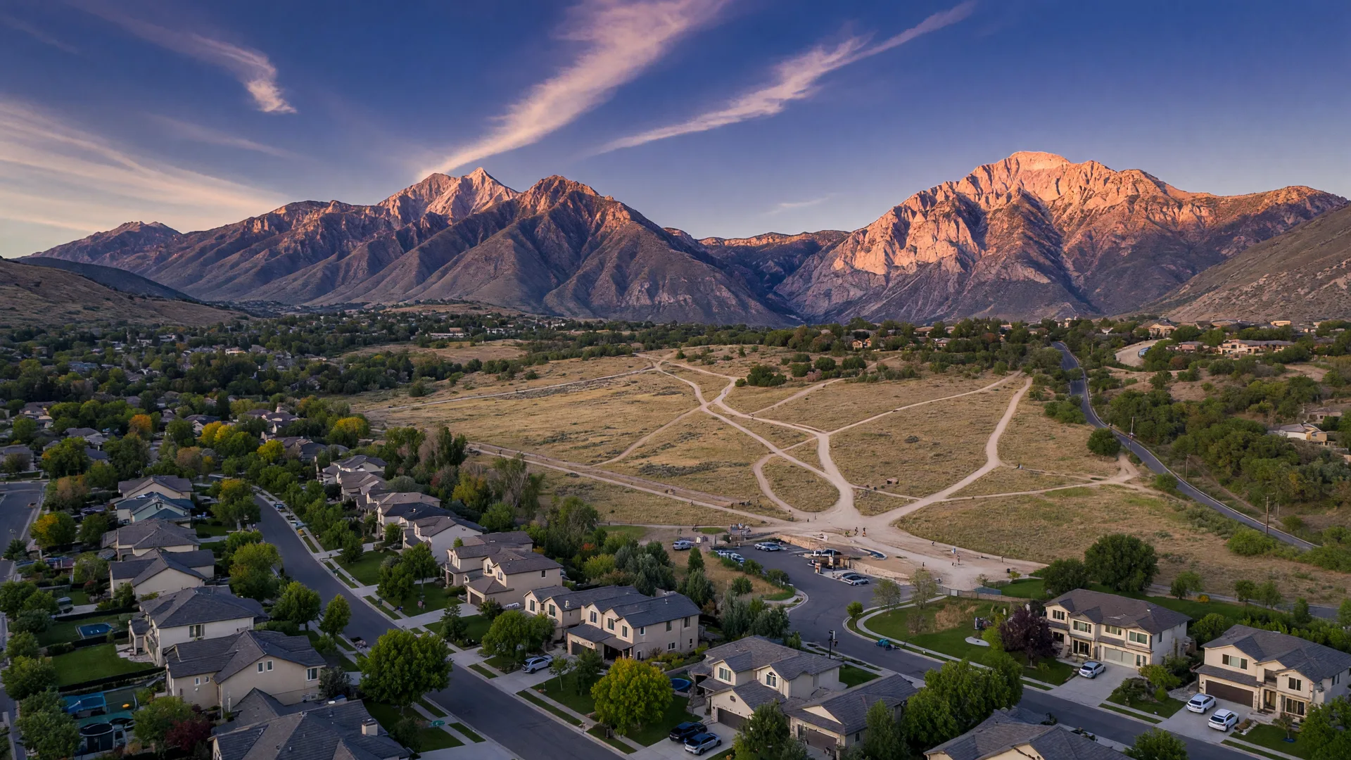 A charming Draper Utah restaurant patio scene at golden hour with string lights and warm mountain-western ambiance, with mountain silhouettes visible in fading twilight