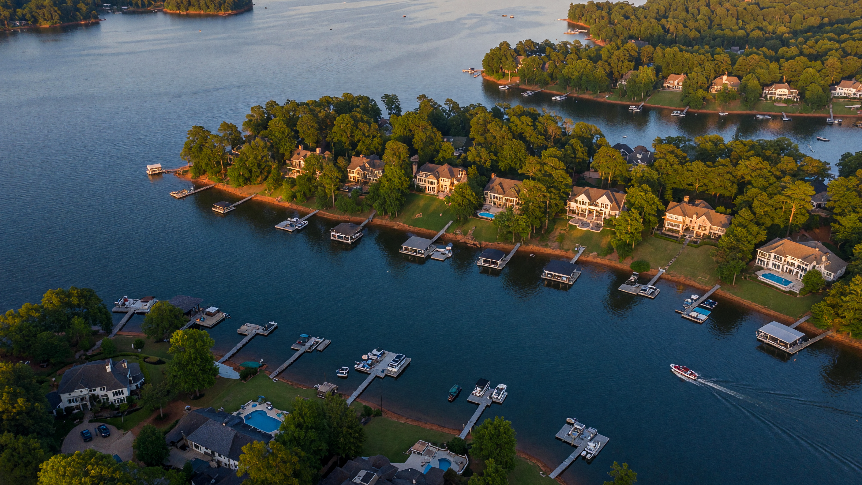 Luxury waterfront home on Lake Norman southern shore near Mooresville NC with private dock, large windows overlooking the water, and manicured lawn sloping to the shoreline