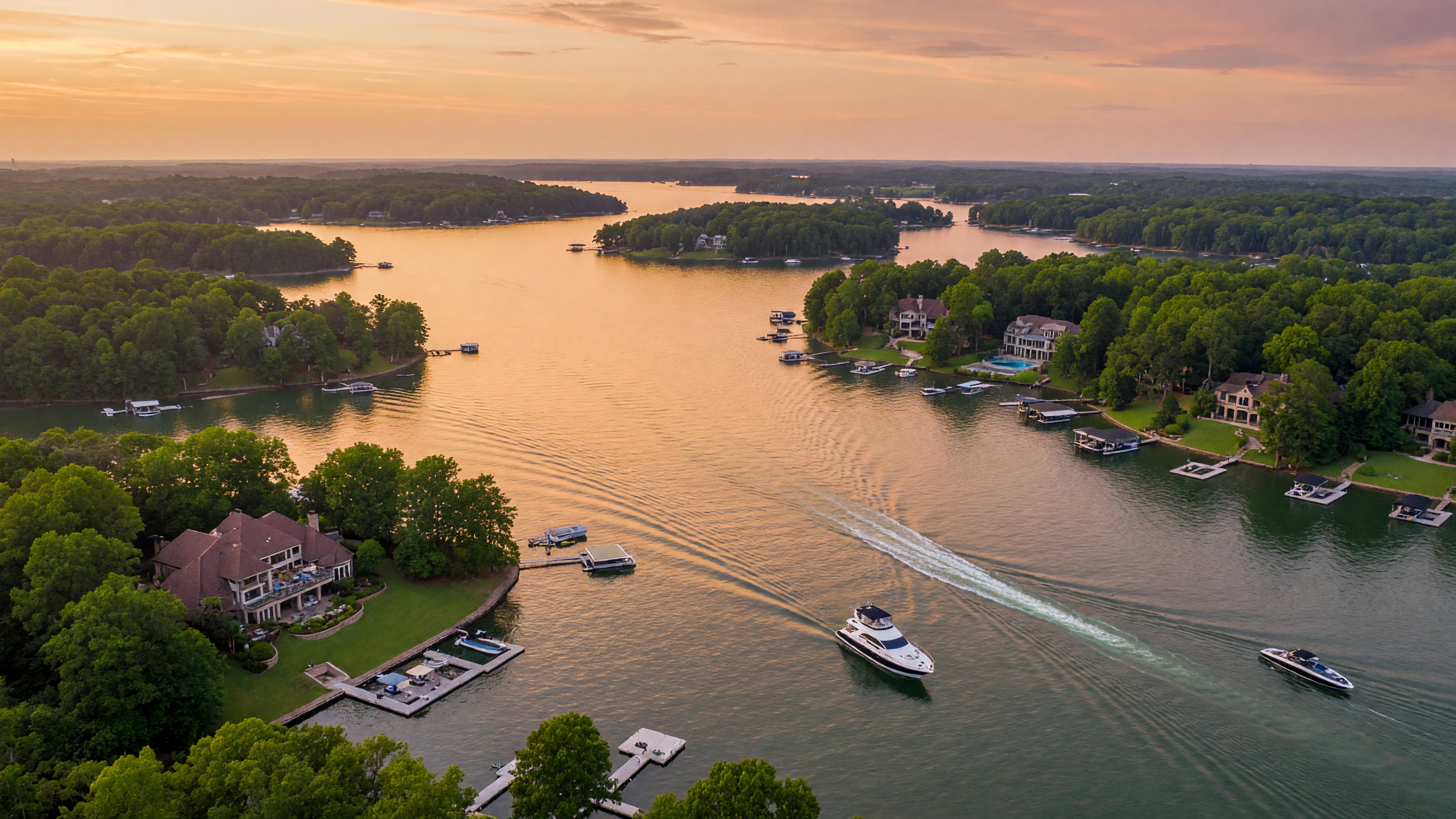 Family enjoying a summer day cruising on a boat across the sparkling blue waters of Lake Norman with waterfront homes visible along the shoreline