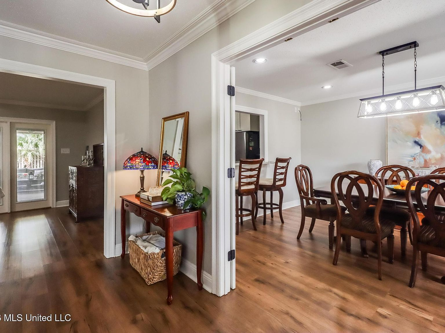 Entryway looking into the dining area with dark wood-look flooring