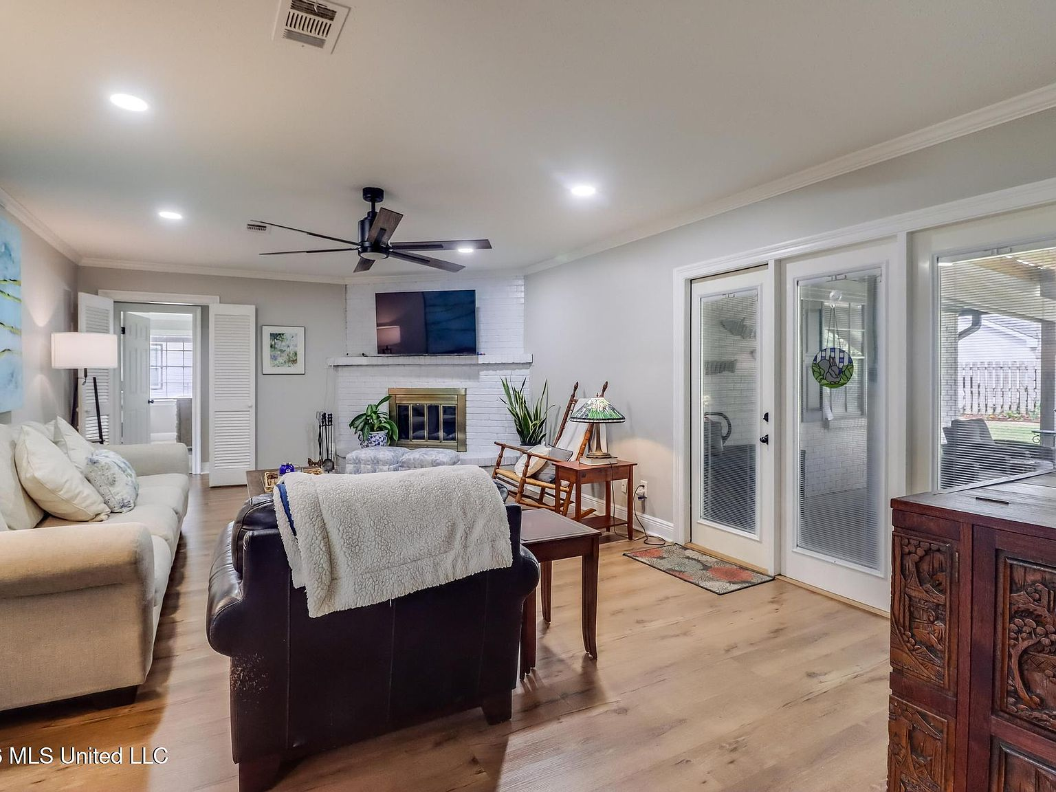Living room with white-painted brick fireplace and wood-look plank flooring