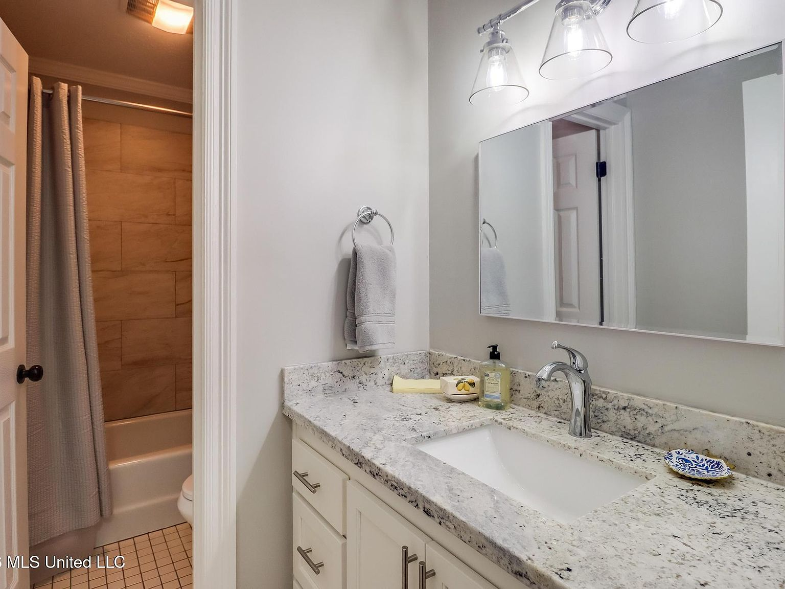 Bathroom with granite vanity countertop and white shaker cabinetry