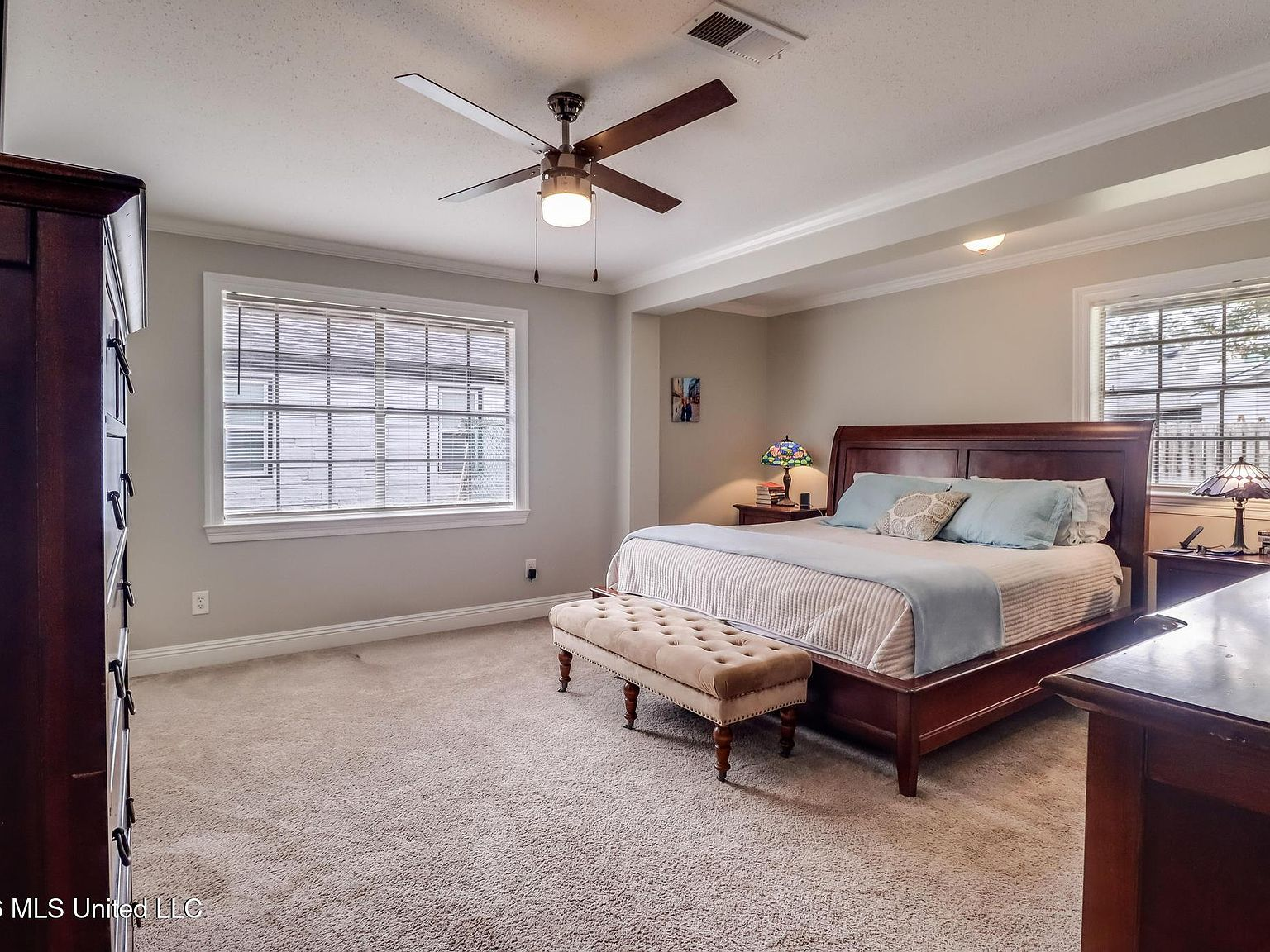 Spacious master bedroom with sleigh bed and white baseboards