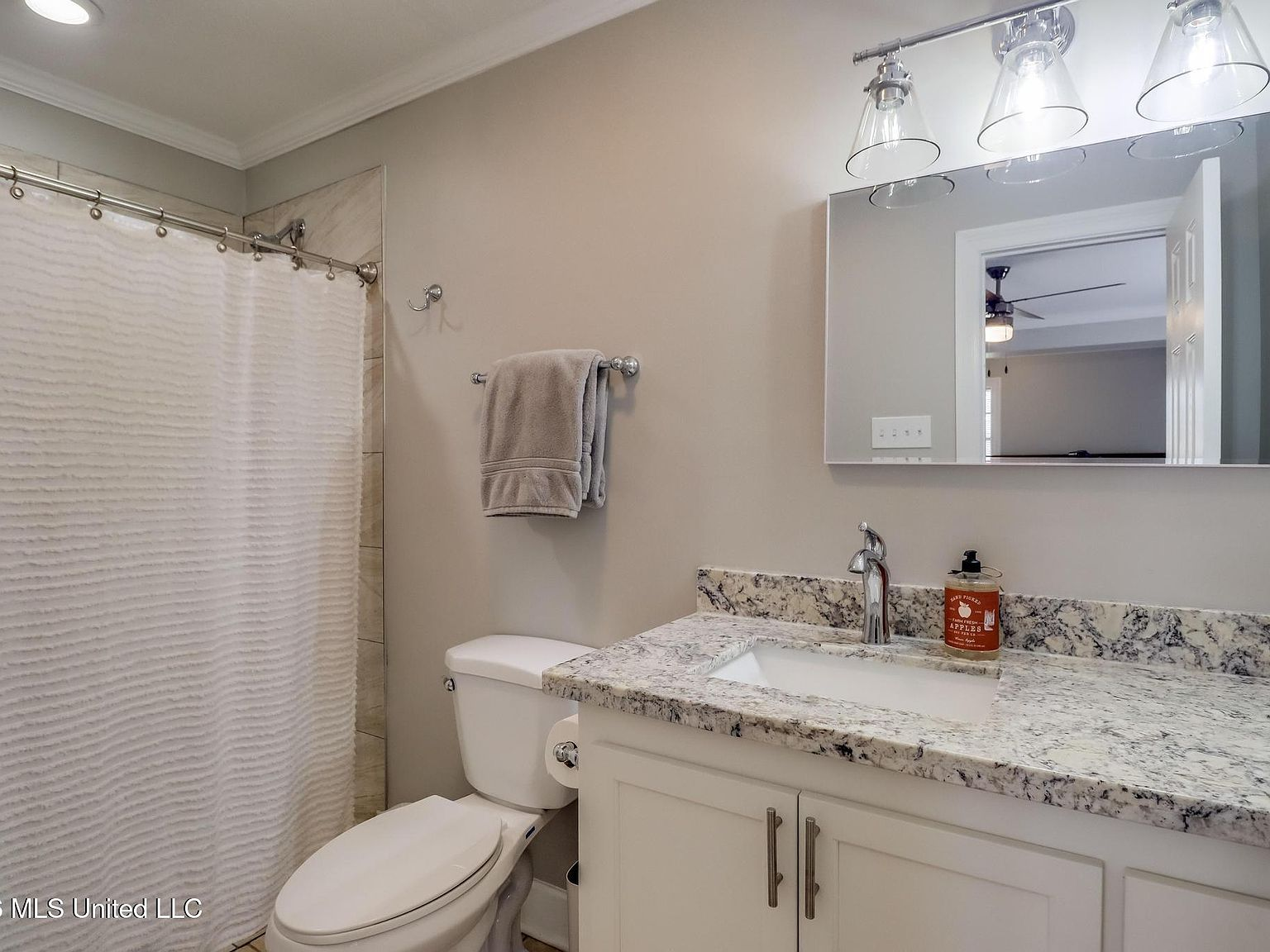 Second bathroom with white vanity, granite countertop, and tiled shower