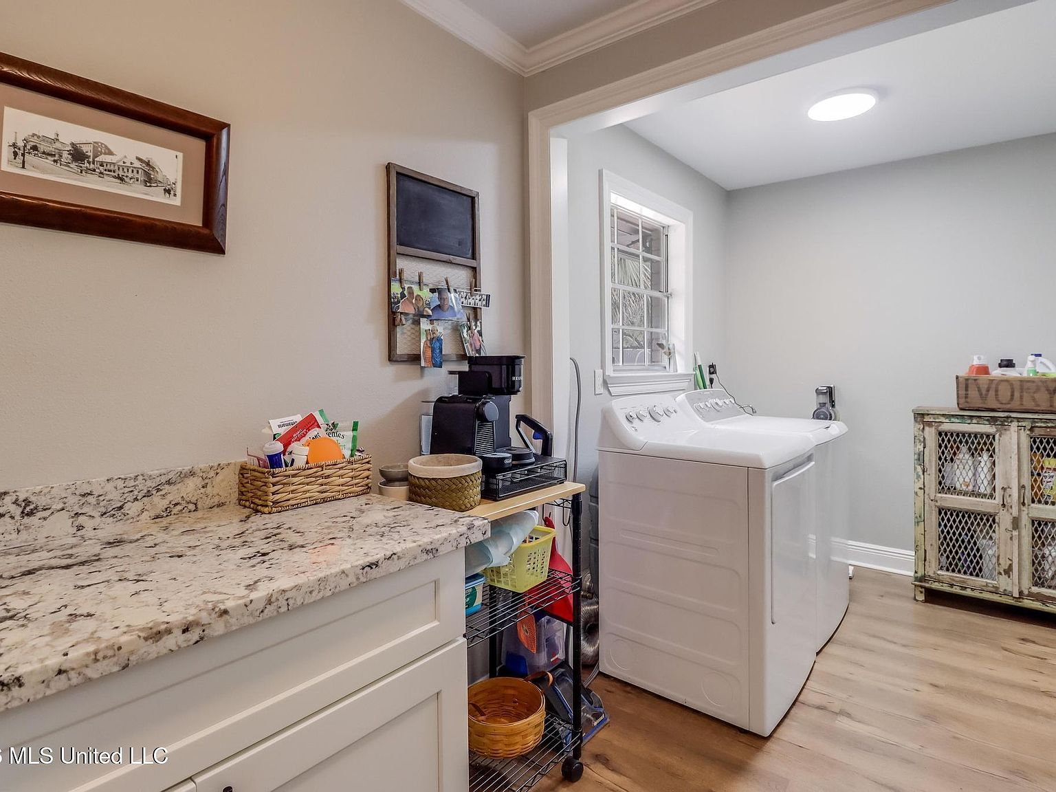 Laundry room with granite countertops, white cabinetry, and washer-dryer