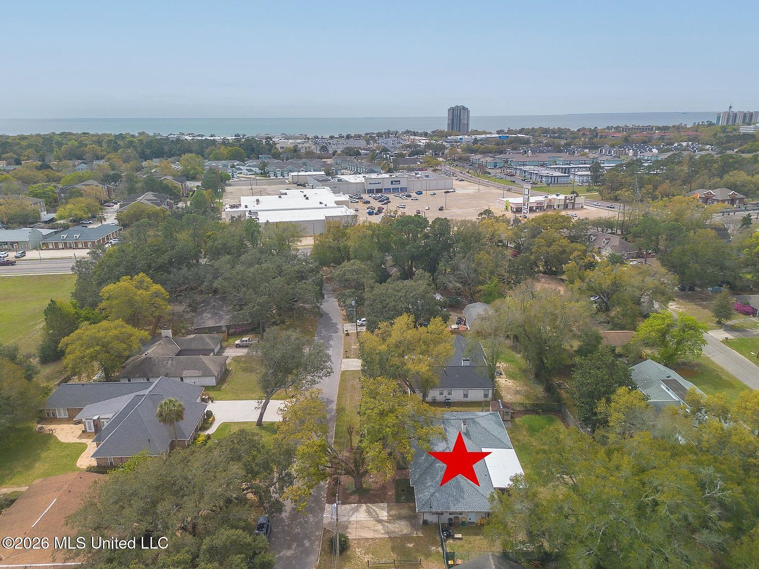 Aerial view of the Biloxi neighborhood with tree canopy and Gulf Coast in the distance